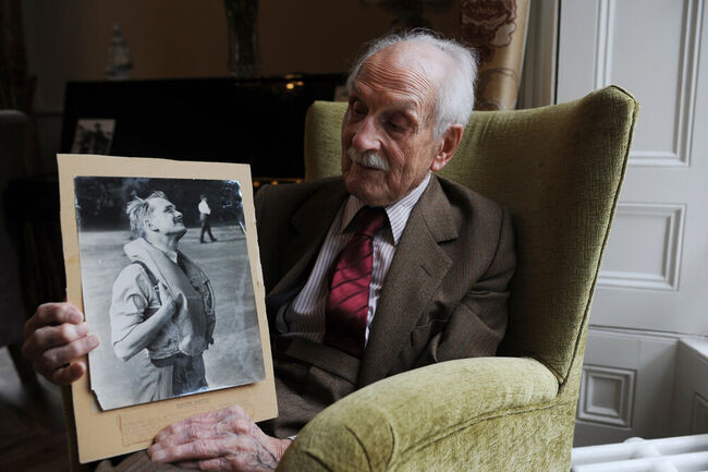 Paddy Hemingway at home holding photo of himself in uniform in RAF