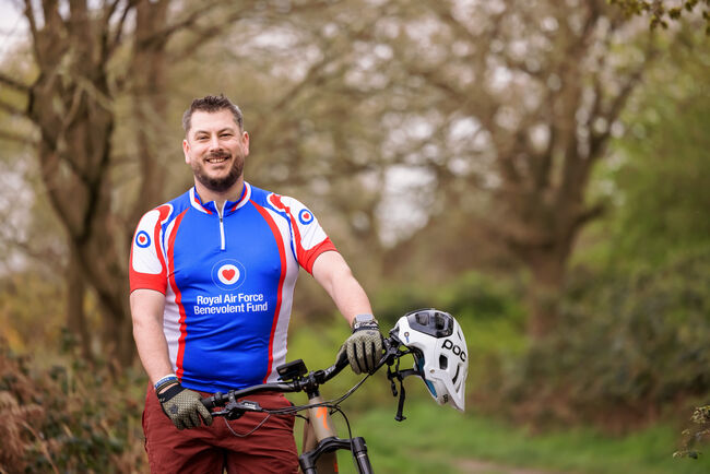 Neil wearing Fund top posing with his bike in the woods